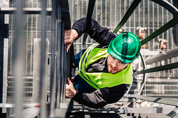 Young male technician climbing ladder in industry