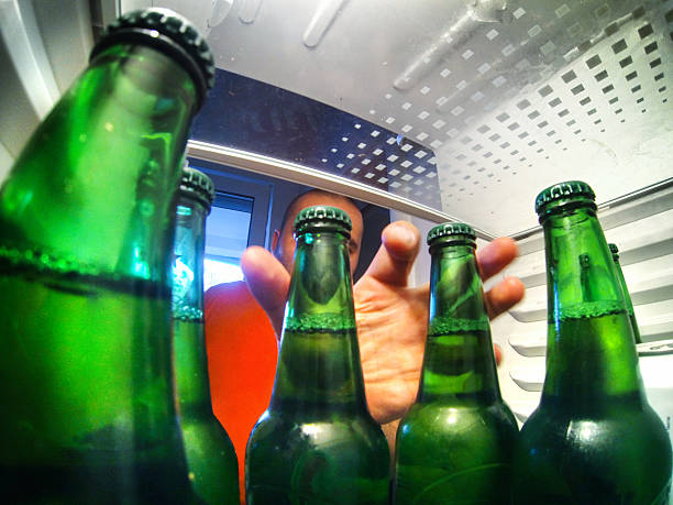 Let's have a beer. Closeup fisheye view of unrecognizable adult man grabbing couple of bottle of beer fromt his fridge. Shot from inside the fridge. Beer bottle are green and the man is wearing orange shirt. fish eye effect stock pictures, royalty-free photos & images