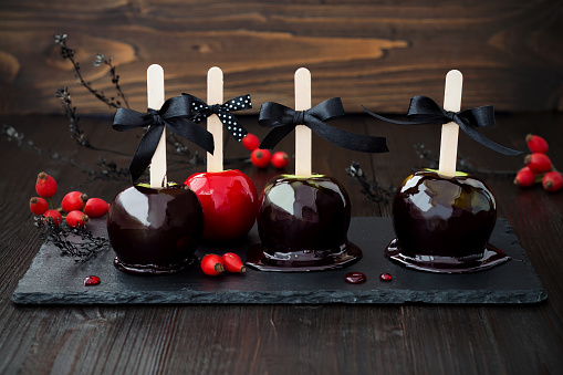Black red poison caramel apples. Traditional dessert recipe for Halloween party. Selective focus.
