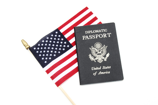 American flag with a USA Diplomatic passport on a white background. Concept of diplomatic or trade negotiations. 