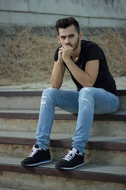 istock young men posing, sitting on old stairs. 490633464