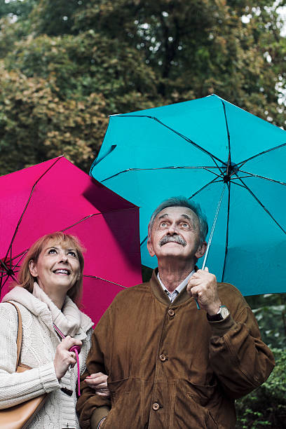 istock Old couple with umbrellas in the rain 490635288