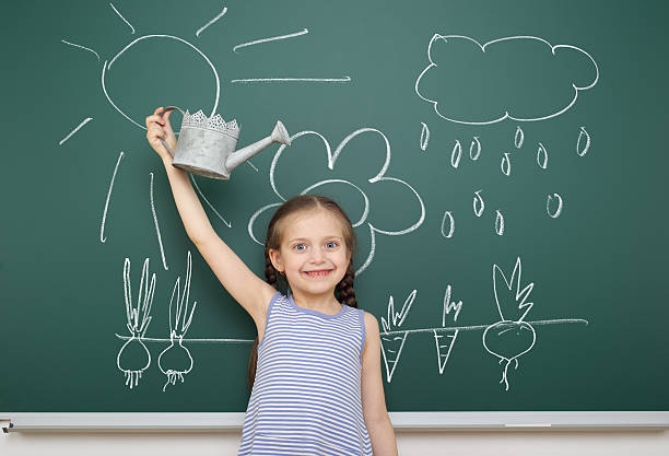 istock girl with watering can drawing on school board 490637302
