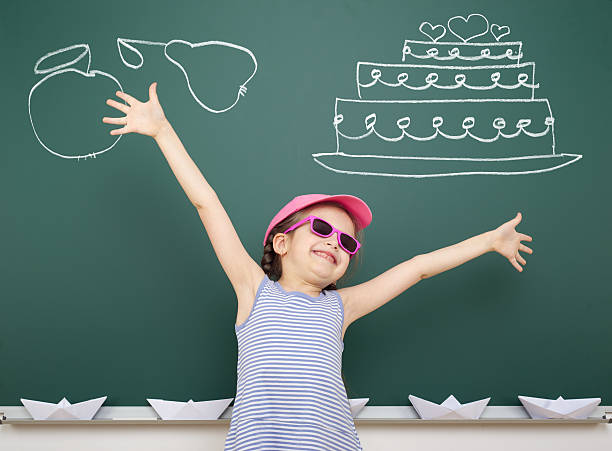 istock girl drawing cake and fruit on school board 490637840