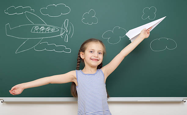 istock girl drawing plane on school board 490637916