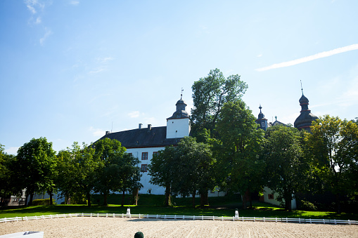 Bad Berleburg, Germany - August 22, 2015: Sidewview of baroque Berleburg in summertime. View over garden and grounds, In foreground is sand of riding grounds.
