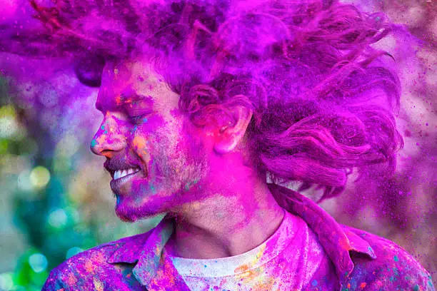 Young man covered in colored dye celebrating Holi festival in Jaipur, India.
