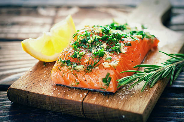 Salmon Fillet Raw salmon on a cutting board with fresh spices cooking with garlic stock pictures, royalty-free photos & images