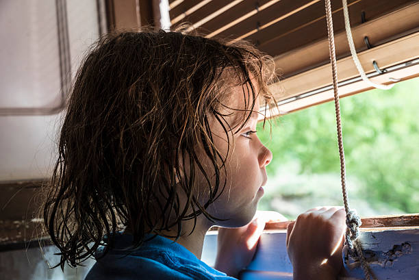 Girl looking out the window Pensive little girl looking out the window at the sunshine Sunblind stock pictures, royalty-free photos & images