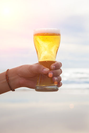 Young woman hand holding a refreshing beer on the beach