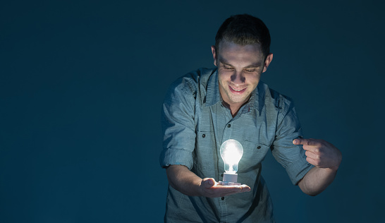 Creative business man looking at a light bulb and thinking about new ideas â creativity concepts