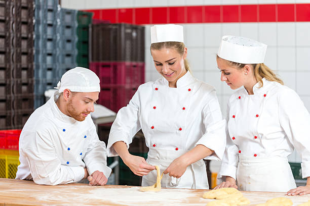 istock apprentice in bakery making pretzels and sceptical bakers watching 490647678