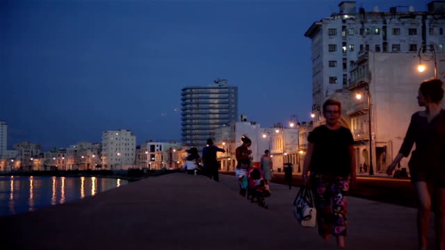 People walking in The Malecon at sunset in La Havana city in Cuba.