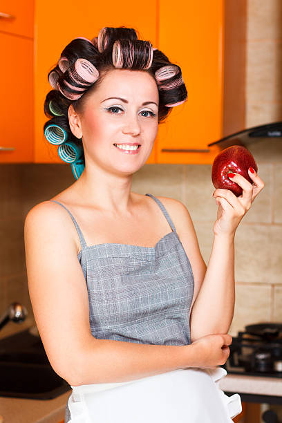 middle-aged woman housewife in the kitchen with apple stock photo