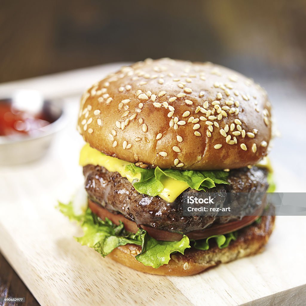 burger with sesame bun and melted cheese close up super thick burger with sesame bun and melted cheese close up, shoy with selective focus. Bun - Bread Stock Photo