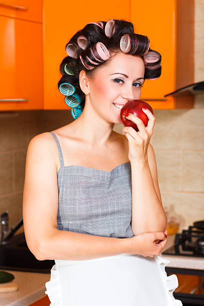 middle-aged woman housewife in the kitchen with apple stock photo