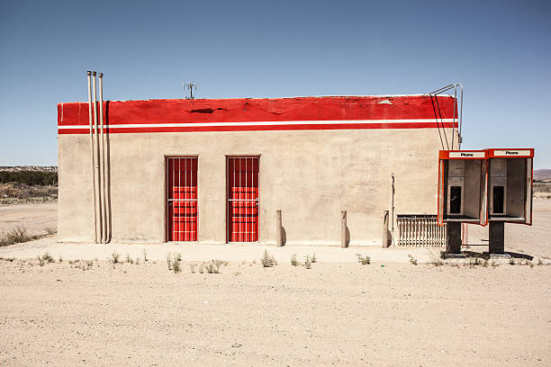 red doors and red painted stripe on building exterior with adobe walls and old phone booths.  horizontal composition.
