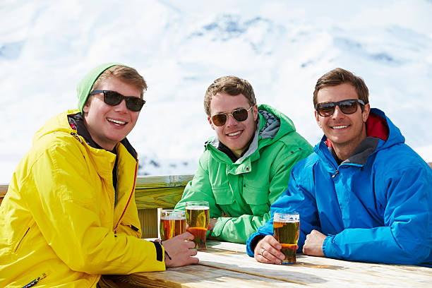 grupo de hombres jóvenes disfruta de una bebida en el complejo turístico de esquí - apres ski friendship skiing enjoyment fotografías e imágenes de stock