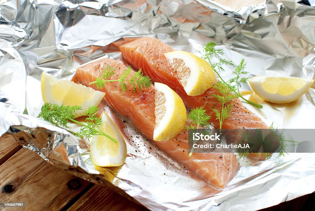 Raw fish fillets Fresh salmon fillets with lemon wedges and dill over foil Foil - Material Stock Photo