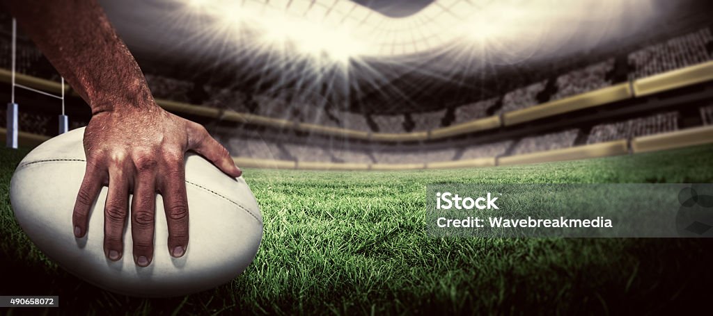 Composite image of rugby player scoring try Close-up of sports player holding ball against rugby pitch Rugby - Sport Stock Photo