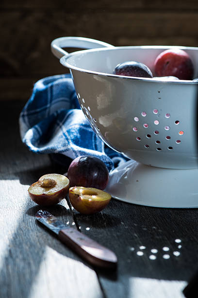 Fresh plums in rustic colander