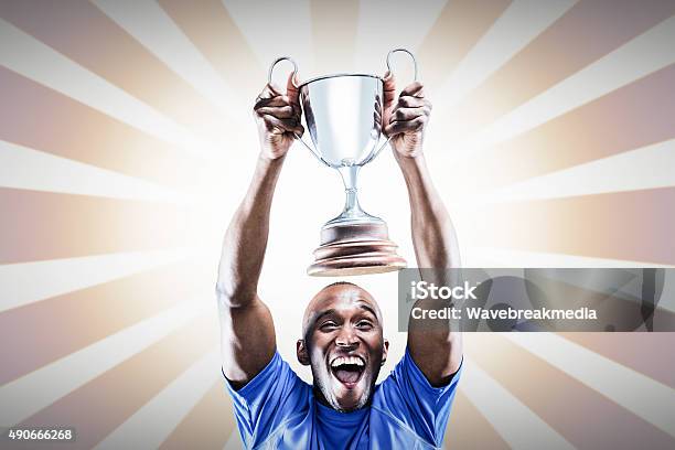 Composite Image Of Happy Athlete Cheering While Holding Trophy Stock Photo - Download Image Now