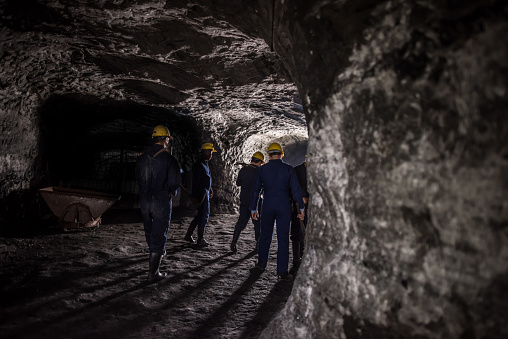 Group of miners working at the mine and walking through a tunnel