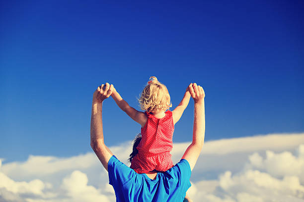 istock father and little daughter on shoulders play at sky 490669578