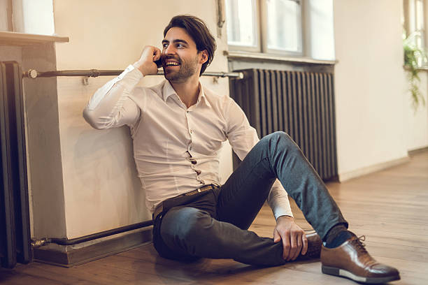 istock Happy businessman relaxing on floor while talking on cell phone. 490673548