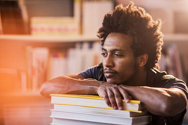 istock Young African American man relaxing on stack of books. 490684660