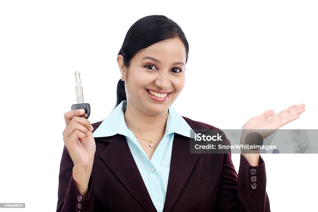 Happy young business woman holding key Happy young Indian business woman holding key against white background Adult Stock Photo