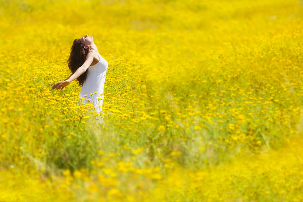 Pretty woman sitting in the nature with her arms spread widely