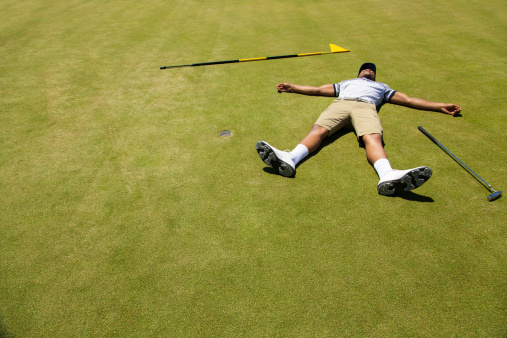 African golfer lying on putting green with his arms and legs open wide feeling exhausted. Langebaan, Western Cape, South Africa