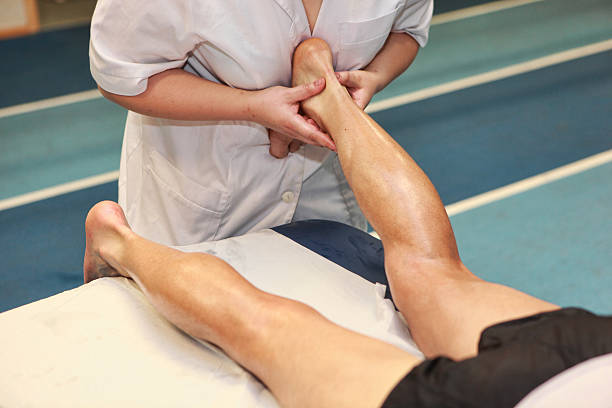 masseuse massaging athlete s Achilles tendon after running stock photo