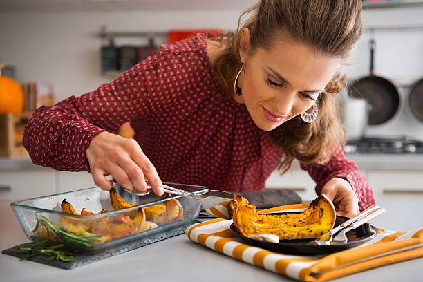 istock Elegant woman leaning over dish as she is serving pumpkin 490691328