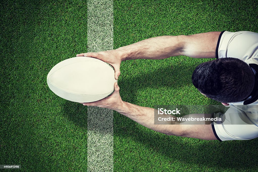 Composite image of a rugby player scoring try High angle view of man holding rugby ball with both hands against pitch with line Rugby - Sport Stock Photo