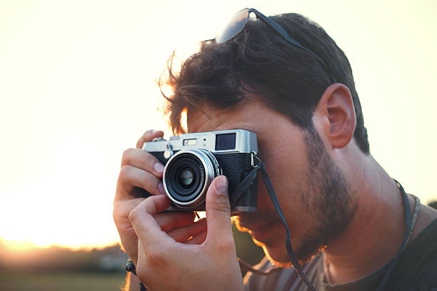 istock Man shooting with vintage camera at sunset 490692060