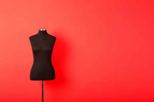 Female mannequin torso  against red background.