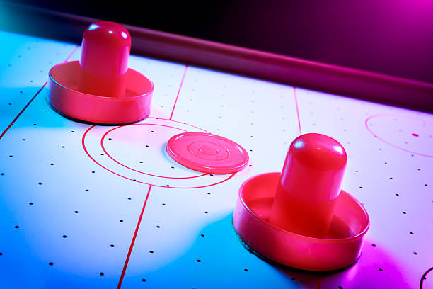 Dramatic lit air hockey table with puck and paddles stock photo