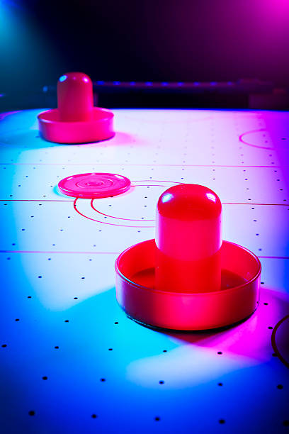 istock Dramatic lit air hockey table with puck and paddles 490694643