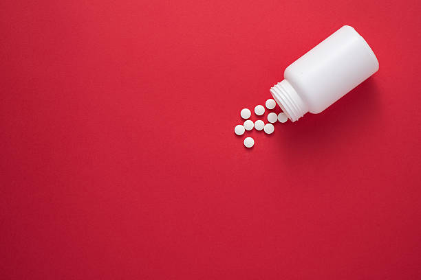 Pills spilling from a bottle Pills spilling from a bottle. Red background. View from the top spilling photos stock pictures, royalty-free photos & images