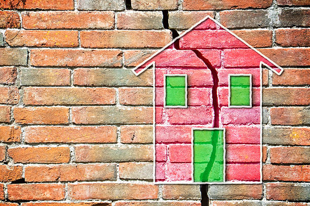 Cracked brick wall with a colored house drawn on it Cracked brick wall with a colored house drawn on it crevice photos stock pictures, royalty-free photos & images