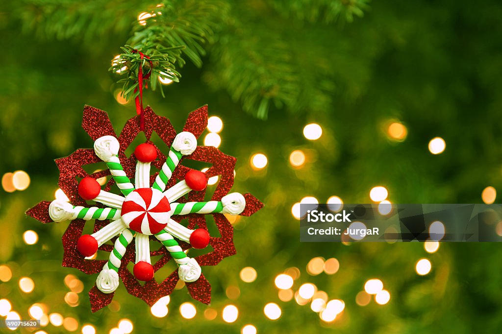 Colorful Christmas Ornament Hanging on Christmas Tree with Blur Lights Close-up of a colorful Christmas ornament in red, green, and white colors. Focus is on the ornament which is hanging on a branch of a beautiful green Christmas tree, while the rest of the tree and white Christmas lights is blur in the background providing space for text. 2015 Stock Photo