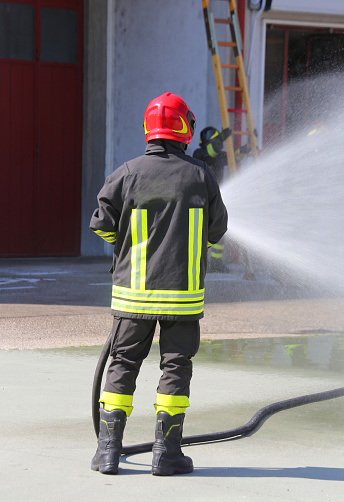 Firefighter sprays water with the spear fighting during the exercise in the fire hall