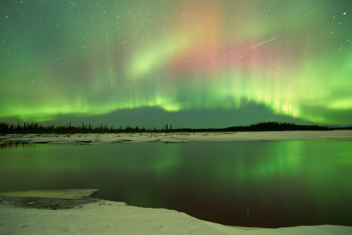 Colorful Aurora Borealis Northern Lights over lake and reflections in lake
