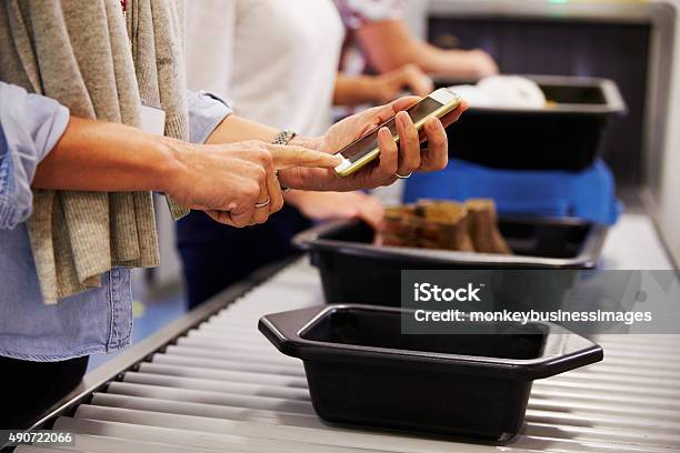Man Checking Mobile Is Charged At Airport Security Check Stock Photo - Download Image Now