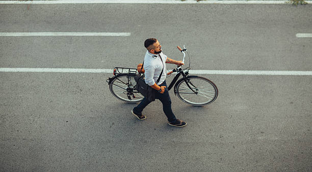 Businessman Pushing Bicycle and going home late. Young Businessman pushing his city bicycle. He has tattoos and hipster haircut. Riding city styles bicycle to and from work. Going home late from office. Top view. top view on people walking and cyclists riding stock pictures, royalty-free photos & images
