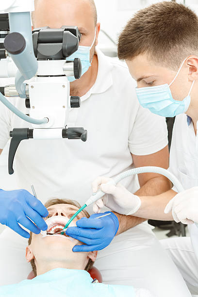 стоматолог, с использованием стоматологического микроскоп в ходе проверки - masc стоковые фото и изображения