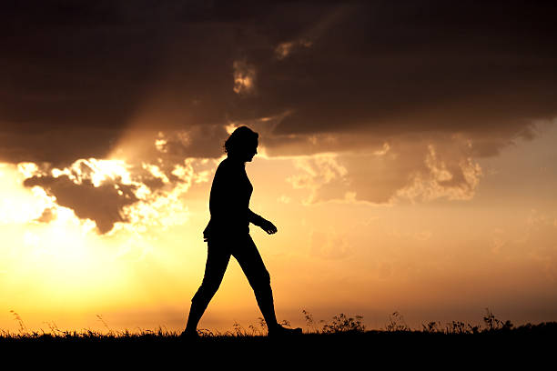 istock Silhouette of woman walking against bright sky 490735511