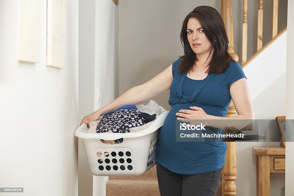 Stressed Pregnant Woman Doing Chores At Home Trying to cope with daily chores during pregnancy Pregnant Stock Photo
